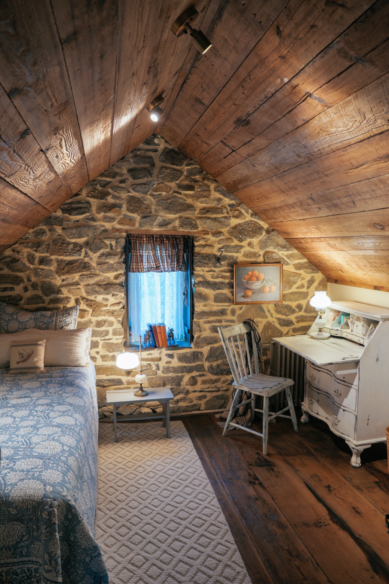 Attic bedroom with hewn rafters against a fieldstone gable wall